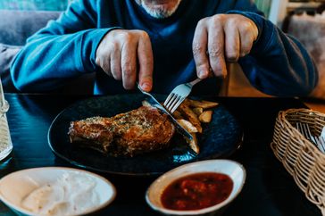 A man cuts into a piece of meat during dinner