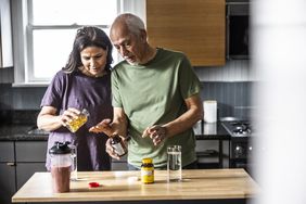 senior couple adding vitamin c and zinc to a smoothie at home