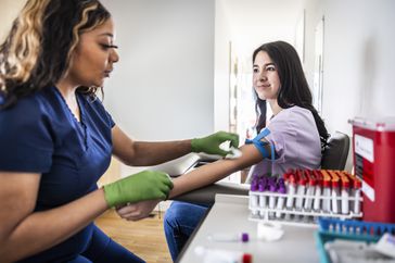 A healthcare provider performs a blood test on a young woman