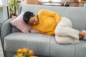 Person lying on couch with bad cramps due to impacted bowel