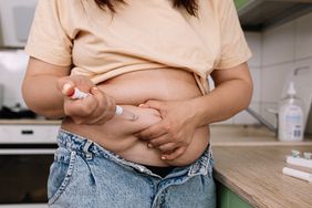 person injecting weight loss medication into stomach