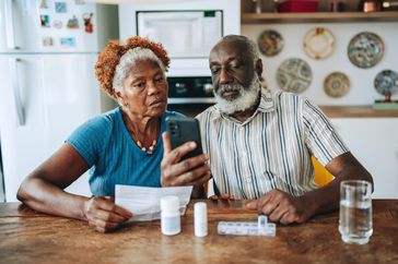 Couple looks at their phone and reads instructions to take their medicine.
