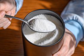 Close-up of a heaped spoon of sugar scooped from a metal can.