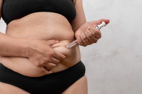 person injecting ozempic medication into her stomach