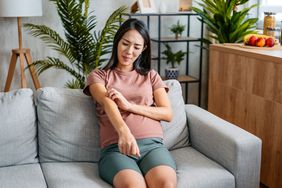 Pregnant person sitting on the couch itching allergic reaction rash on arm