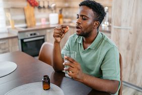 A man takes a supplement with a glass of water