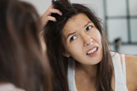 Person scratches itchy scalp in the mirror.