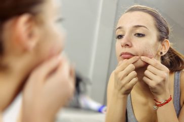 woman looking at her skin in the mirror
