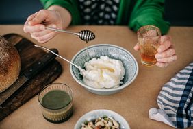 A woman adding honey to yogurt