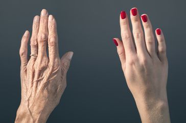 elderly woman's hand beside young woman's hand