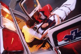 emergency medical technicians wheeling in person on a gurney 