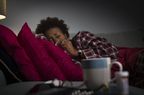 Woman with pneumonia coughing and laying down on couch.