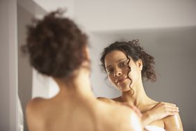 Person in a towel examining body in the mirror.