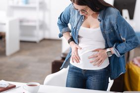 A woman holds her hands to her abdomen