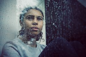 Person looks out of a rainy window.