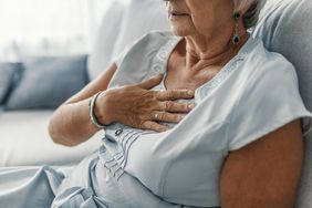 Woman having a pain in the heart area, putting her hand on her chest.