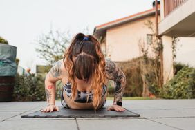 A young woman doing a burpee on a mat outside