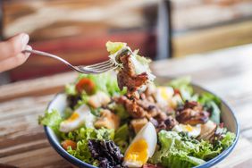 A salad in a bowl with chicken and egg, on the wooden table