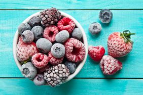 Frozen or frosted berries bowl placed on sea blue wooden background.