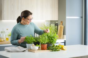 Woman arranging cooking herbs for weight loss in planted pot. 