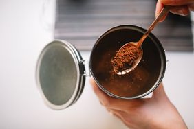A hand scooping up instant coffee from a jar