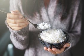Midsection Of Woman Holding Rice In Bowl