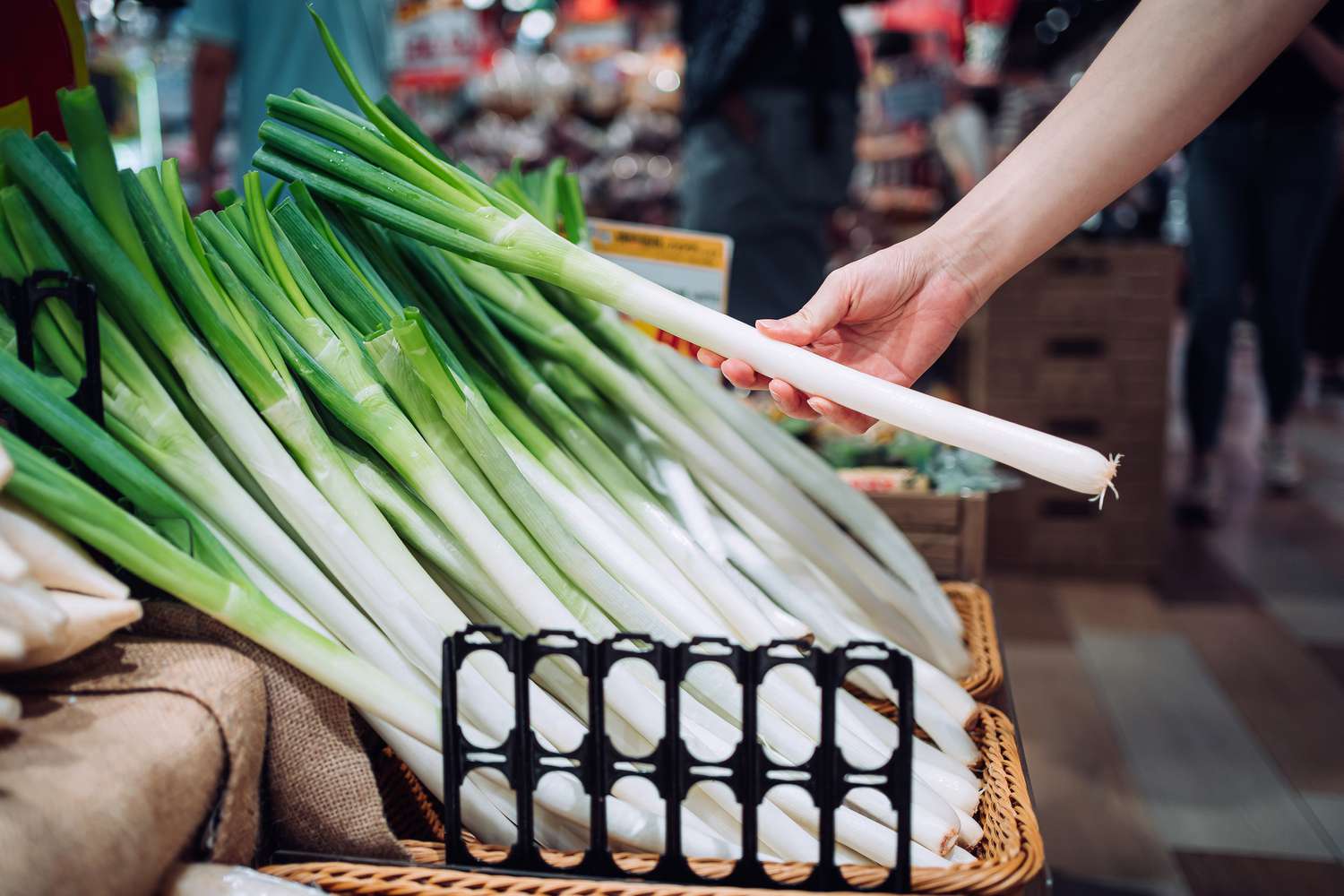 A hand picking a fresh leek from basket