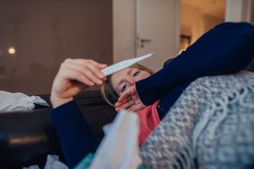 sick woman taking her temperature 