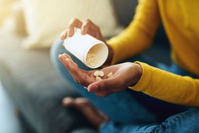 Young woman taking supplements on a couch