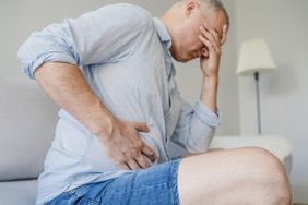 Man holding right side of stomach (near liver) in pain