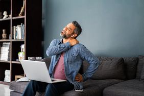 person experiencing neck and shoulder pain while working on couch