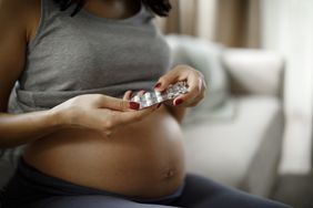 pregnant woman taking a pill at home
