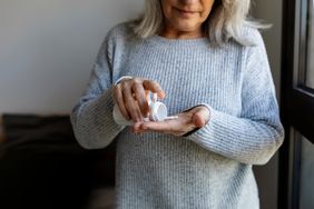woman standing by window taking pills