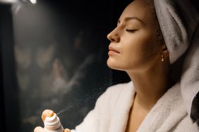 Woman spraying body oil on herself