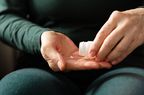 person taking small white pill from pill bottle