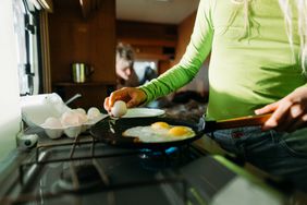 woman breaking eggs into frying pan
