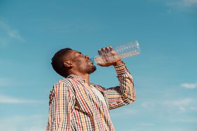 man drinking water from plastic bottle