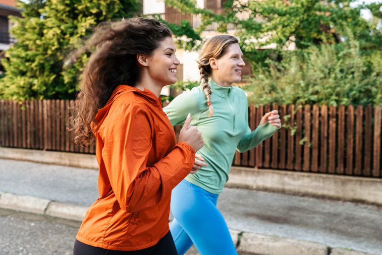 Two female friends jogging together in the neighborhood.