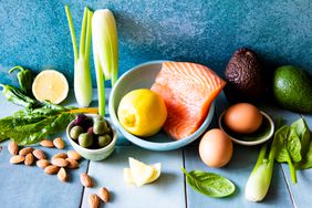 Fresh raw food ingredients seafood, avocado, vegetables, fruit, salmon fish, olives on tile surface