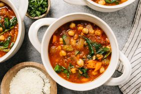 An overhead photo of a bowl of chickpea stew with parmesan cheese and parsley on the side.