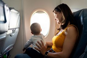 Proud mother caring her son on airplane.