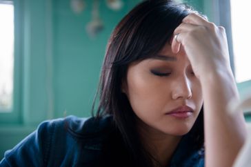 Woman holding her hand to her head in pain