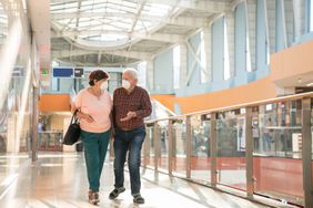 Man and women walk together in a mall with face masks on. 