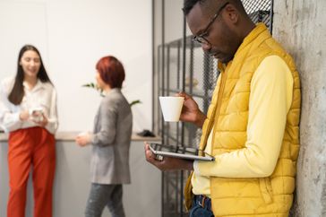Man using tablet and drinking coffee at office coffee break