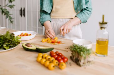 Woman preparing a salad at a kitchen counter.