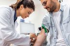 phlebotomist taking blood sample of male patient 