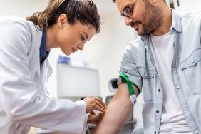 phlebotomist taking blood sample of male patient 