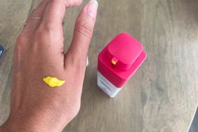 The Drunk Elephant A-Passioni Retinol Cream on the back of a hand next to the bottle