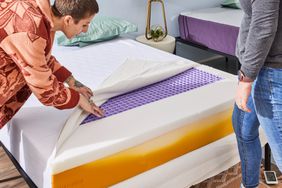 A person setting up the Purple NewDay Mattress on a bed frame