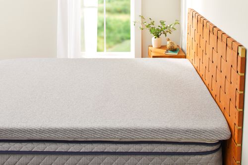 The Casper Sleep Comfy Mattress Topper on a mattress in a bedroom on a bed frame.